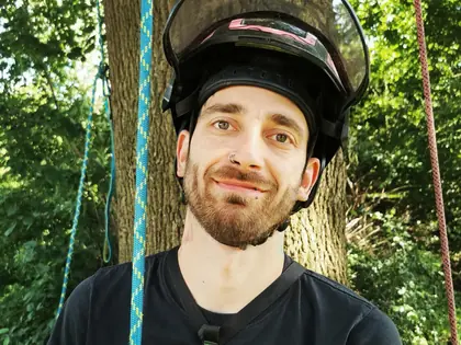 Aaron Ehmke, Baumpfleger von Himmelhoch Baumpflege, mit Kletterhelm vor einem Baum